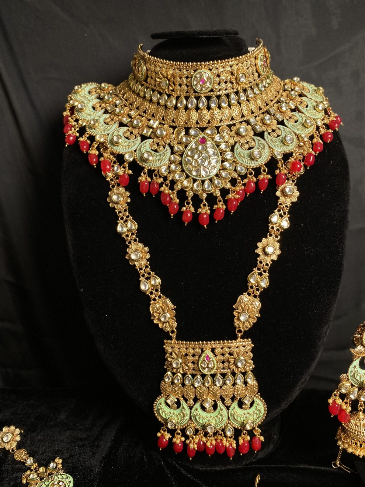 Complete your bridal look with our mesmerizing Indian choker set, featuring a choker necklace, mala, matha patti, jhumkas, hath panja, and nath/nose ring. Each piece is embellished with kundan stones and pearls for a touch of regal elegance.