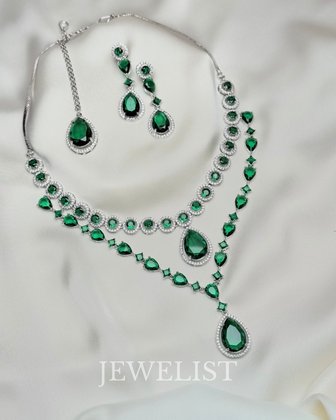 Twilight Brilliance Set by Jewelist.pk – elegant two-layer emerald green necklace set featuring teardrop stones, cubic zircon accents, and matching earrings for bridal and formal wear.