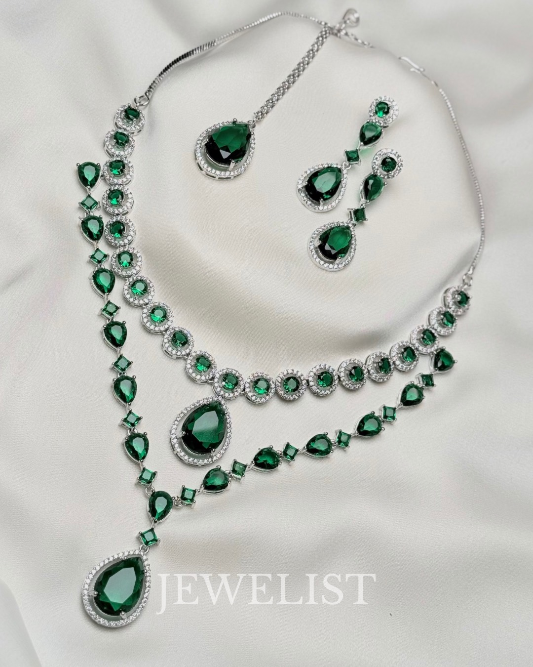 Twilight Brilliance Set by Jewelist.pk – elegant two-layer emerald green necklace set featuring teardrop stones, cubic zircon accents, and matching earrings for bridal and formal wear.