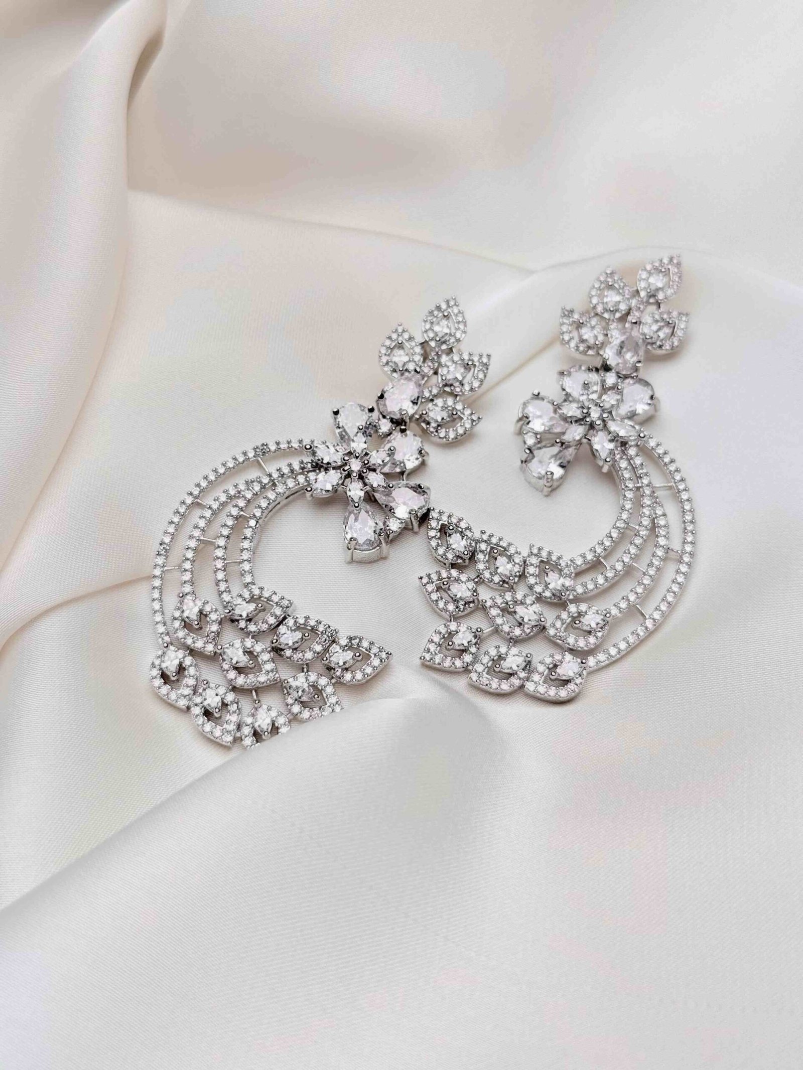 Crescent Leaf Earrings close-up showing silver-tone floral clusters, three sparkling crescent arcs and decorative leaf motifs