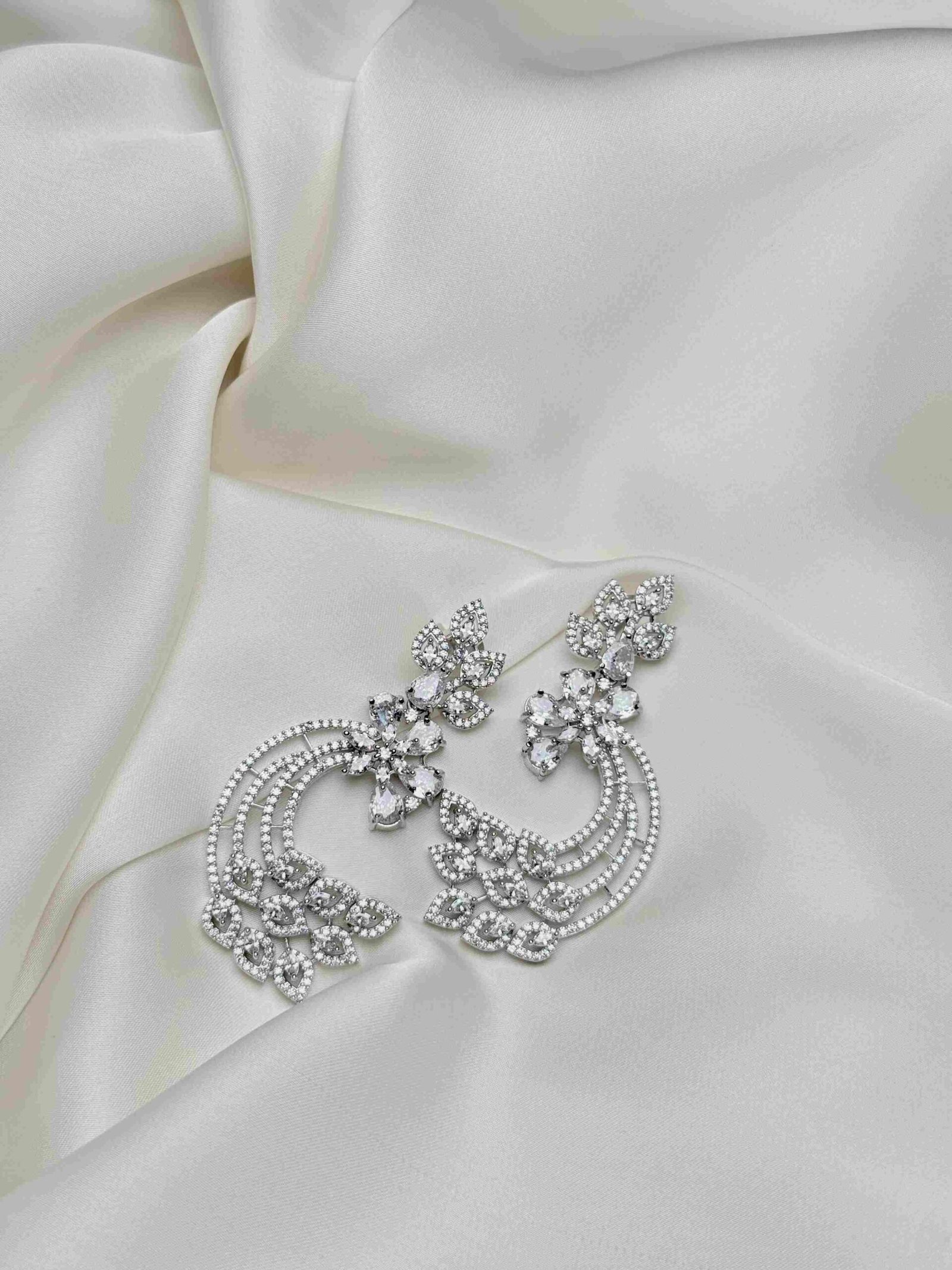 Crescent Leaf Earrings full pair on ivory fabric with silver-tone open crescent design and sparkling leaf-shaped accents